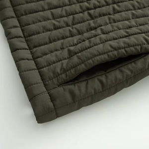 Detail of olive green quilted jacket showing horizontal stitching and side pocket design
