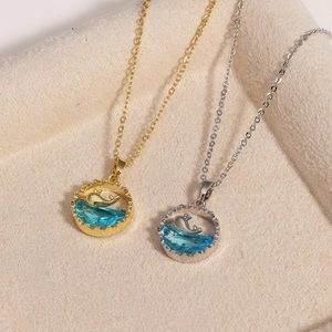 Macro shot of gold and silver whale pendant necklaces with blue gemstone waves