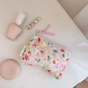 Detailed view of quilted floral cotton mini storage pouch with zipper and cosmetic items