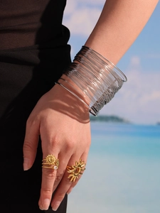 Detail showing layered silver arm cuff and gold sun rings in a bohemian beach style