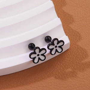 Close-up of flower stud earrings with black and white petals on a tiered display stand