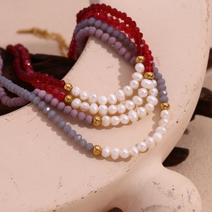Macro detail of handmade necklace with freshwater pearls and red faceted crystal beads