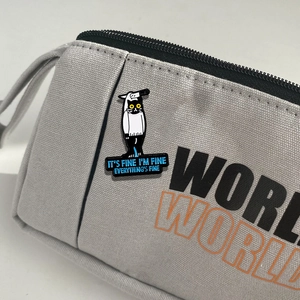 Cartoon cat badge with IT'S FINE text pinned to a gray canvas bag for creative styling