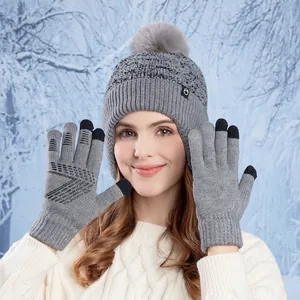 Winter grey knit hat with fur pompom and touchscreen gloves set on a snowy background
