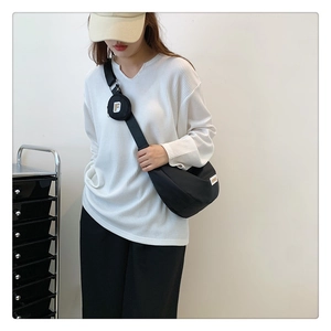 Détail du sac croissant noir avec large bandoulière et petit porte-monnaie rond attaché