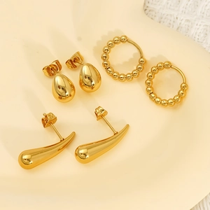 Three-pair gold earring set with teardrop studs, beaded hoops, and sleek curved cones