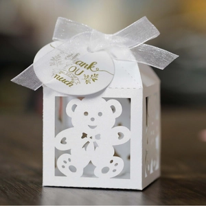 White hollow bear gift box with silk ribbon and gold tag on dark wooden surface