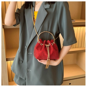 Detail of red rhinestone bucket bag with metal ring handle and gold tassel drawstring