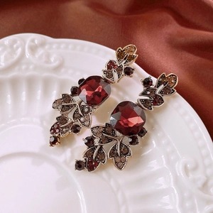 Detailed macro view of vintage earrings with red gemstones on a white embossed plate