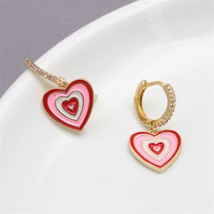 Close-up of gold earrings with layered red, pink and white enamel heart drops