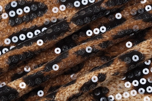 Macro shot of leopard print fabric with shiny silver sequins and detailed textile texture