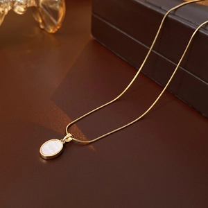 Macro de la chaîne serpent dorée avec pendentif ovale en nacre blanche sur cuir