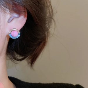 Close-up of pink crystal flower earring with blue beads and diamonds on model ear