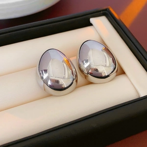Vue macro de boucles d'oreilles argentées en forme de haricot avec fini poli miroir