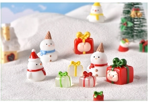 Miniature resin snowmen and pigs in gift boxes placed on artificial snow for Christmas