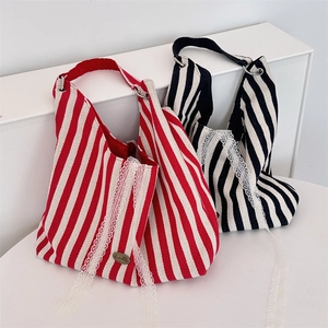 Détail de sacs en toile rayée avec bordure en dentelle blanche et plaque logo en métal