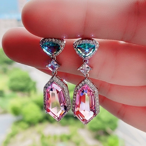 Close-up of dangling earrings with pink and blue step-cut crystals and halo diamonds