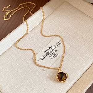 Detailed close-up of tiger eye flower pendant on a golden twisted chain necklace