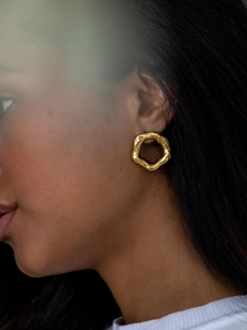 Detail of high-quality golden hexagonal hoop earring with textured hammered finish on model