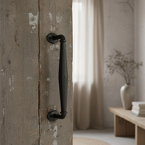Vintage industrial black cast iron door handle with hammered texture on weathered wood