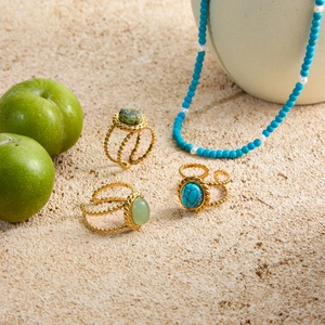 Macro detail of bohemian 18K gold plated steel rings with turquoise stones on sand rock
