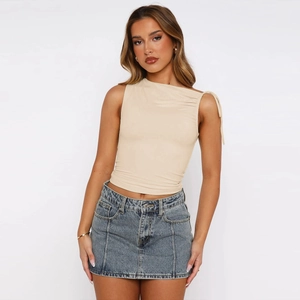 Detail of apricot asymmetric crop top showing the shoulder knot and ruched fabric texture