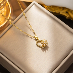 Gold spinning flower and heart pendant necklace displayed in a beige jewelry box