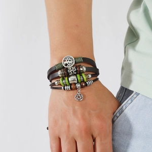 Detail eines Boho-Lederarmbands mit Lebensbaum-Anhänger und türkisfarbenen Perlen am Handgelenk