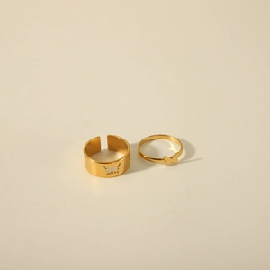 Minimalistisches 18K vergoldetes Edelstahl Schmetterling Paar Ringe Set auf beigem Hintergrund