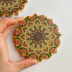 Detailed close-up of a ceramic mandala coaster with embossed gold foil and floral pattern