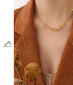 Detail of a double-layered gold necklace with thick and thin chains on a model outfit