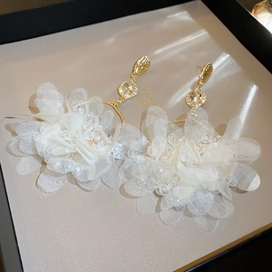 Macro view of white organza flower earrings with crystal beads and gold plating