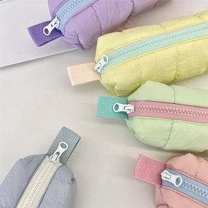 Close-up of quilted macaron color pencil cases with zippers and ribbon handles