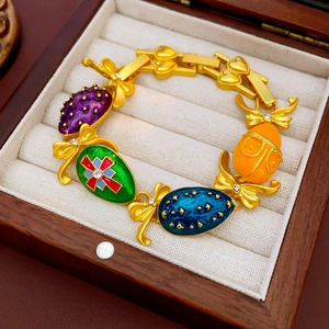 Dettaglio di un bracciale vintage in oro con ciondoli in smalto colorato e fiocchi