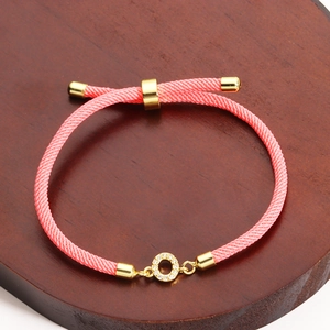 Close-up of pink woven adjustable bracelet with a sparkling gold micro-pave circle charm