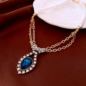 Vintage Goldkette mit blauem Tropfen-Edelstein, Strass und weißen Perlen im Retro-Stil.