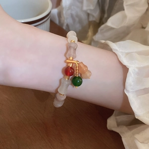 Detail of beaded puppy bracelet with red beads and light brown gourd pendant