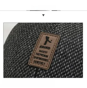 Detailed close-up of dark grey tweed winter baseball cap with premium leather logo patch