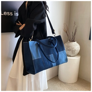 Detail of a denim patchwork tote bag with white stitching and adjustable shoulder strap