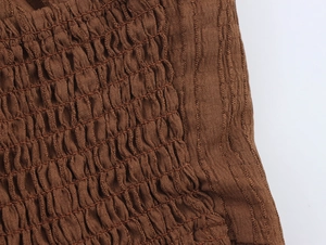 Macro detail of brown smocking and vertical ribbed knit fabric textures on a maxi skirt set