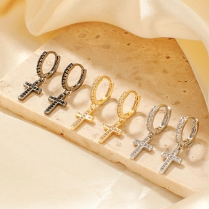 Three pairs of cross hoop earrings in gold, silver, and black finishes on a satin background