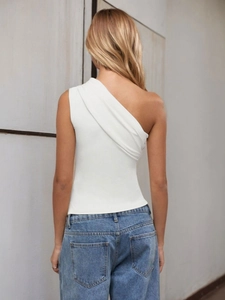 Back view of sexy white one-shoulder knitted top paired with blue jeans in minimalist studio