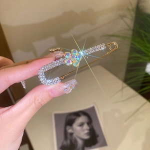 Detail of luxury gold safety pin brooch with sparkling rhinestone flower and crystal inlay