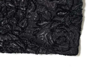Detail von schwarzem Stoff mit 3D-Blumenmuster und schimmernden Pailletten