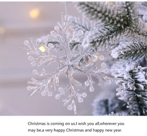 Macro shot of a transparent acrylic snowflake ornament hanging on a snowy Christmas tree branch