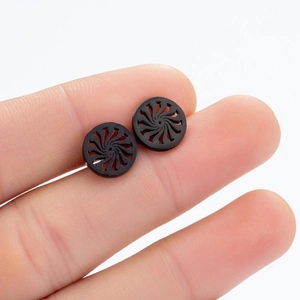 Macro shot of black spiral geometric stud earrings showing matte texture and craftsmanship