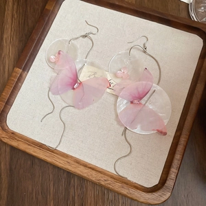 Detail of pink fabric butterfly earrings with shell pieces and silver fringe tassels
