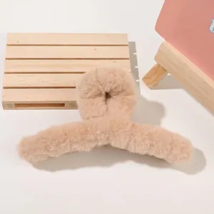 Detail shot of a beige plush hair claw clip showing soft faux fur texture and arched design