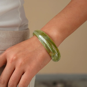 Close-up of a green marble acrylic bangle on a wrist showing artistic swirling patterns