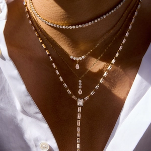 Detalle de collares de varias capas en oro y circón con colgantes de gota en una modelo